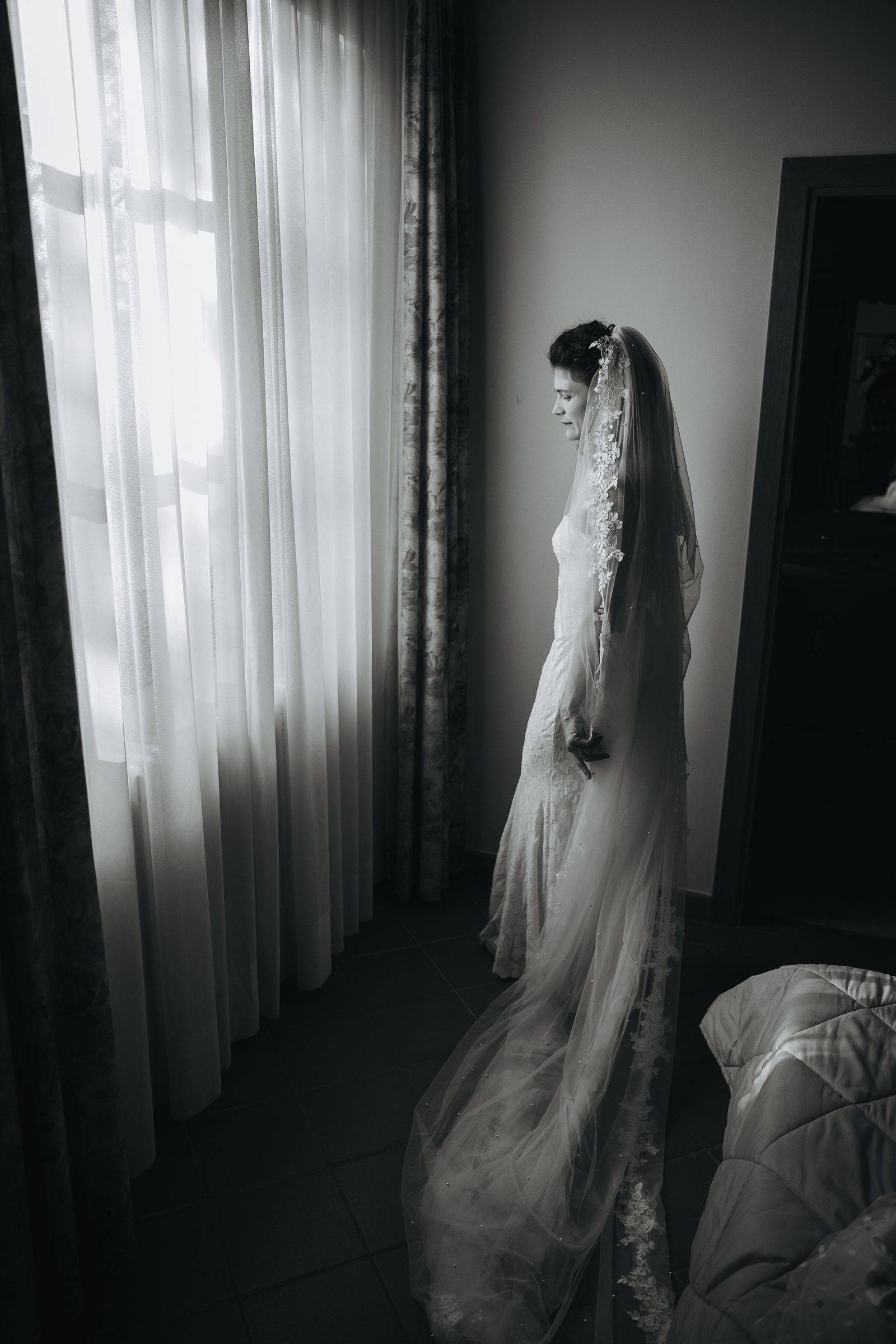 Erika in abito da sposa davanti alla finestra