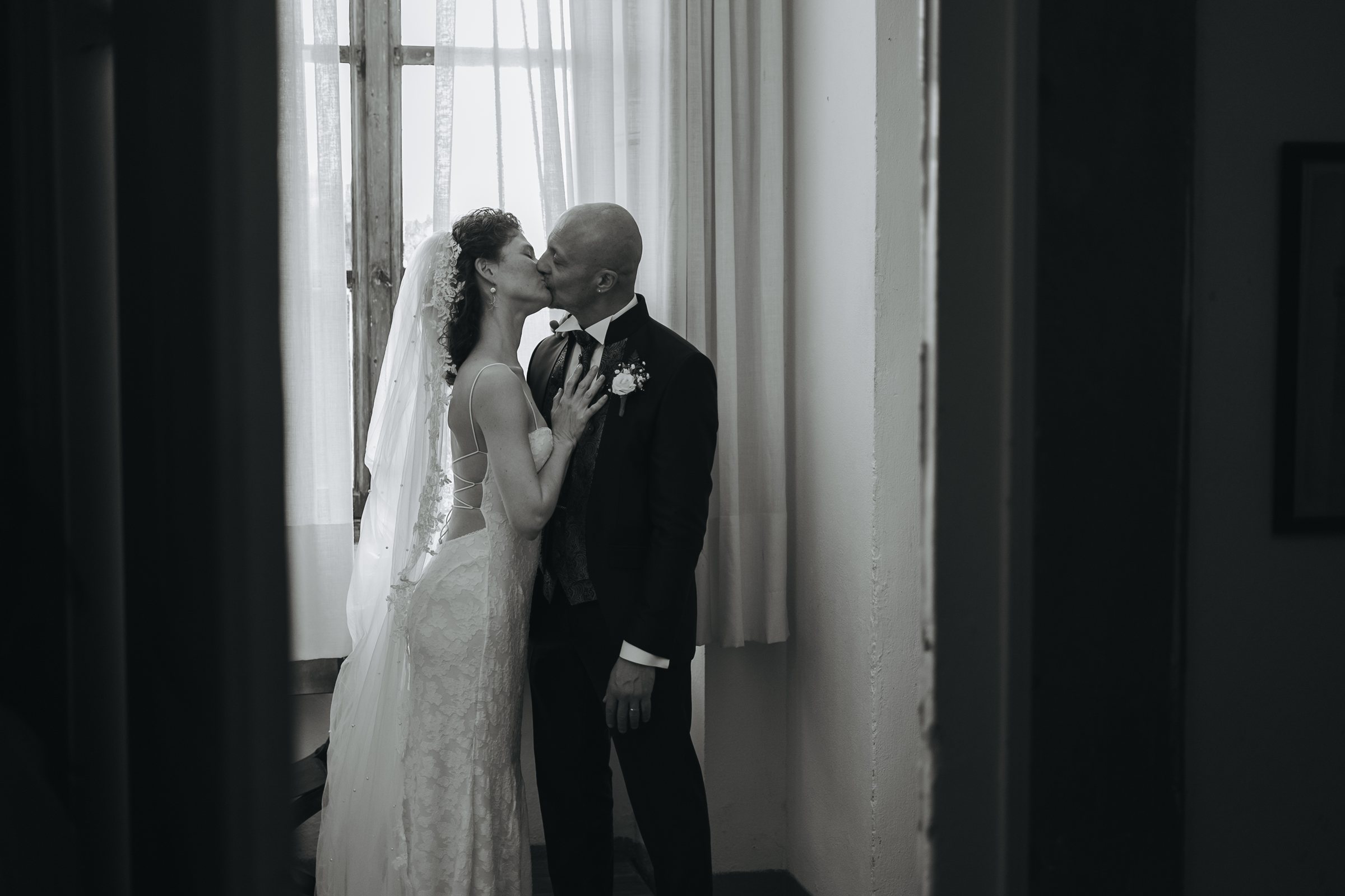 Bacio degli sposi vicino alla finestra in bianco e nero