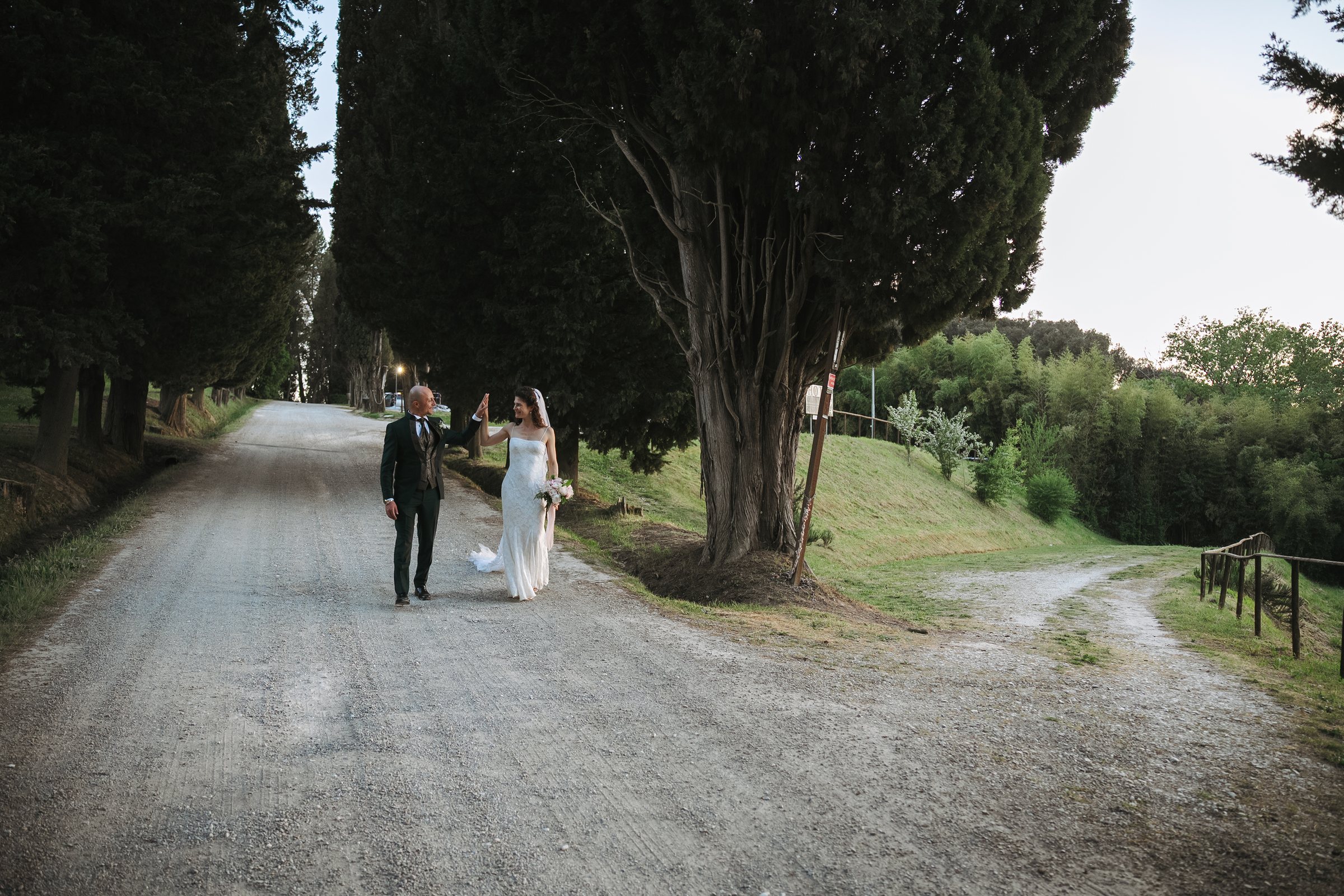 Alessio ed Erika passeggiano sotto i cipressi